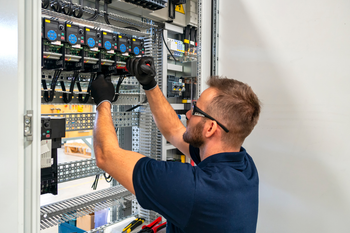 A man is working on an electrical panel in a room.