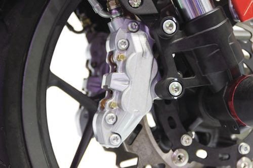 Motorcycle front wheel with silver brake caliper, black rotor, and fork assembly.
