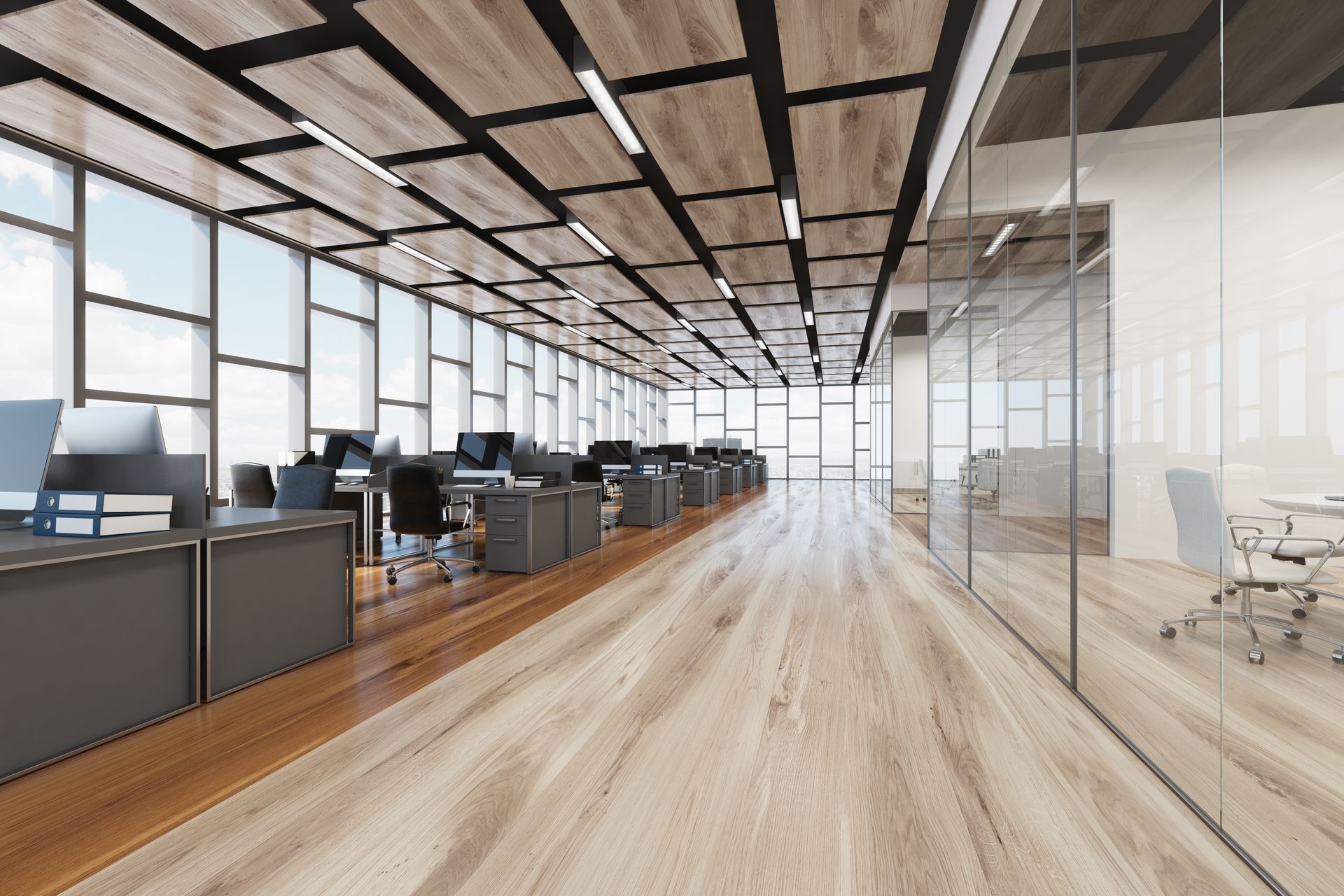 Modern open-plan office with desks, large windows, wood floors, and glass meeting rooms