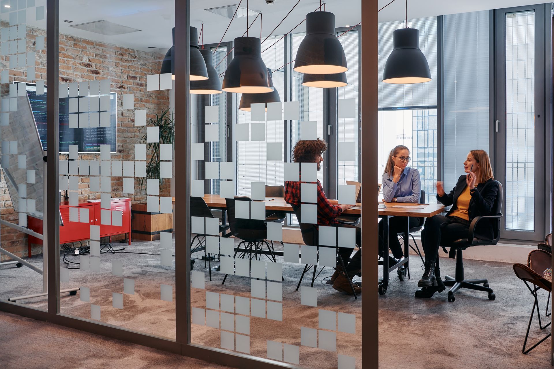 Two people talking at a table in a modern glass-walled office lounge