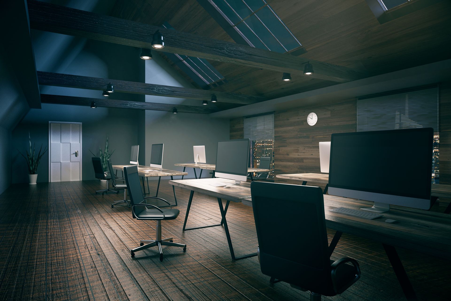 Empty modern office with desks, monitors, and office chairs under cool overhead lighting