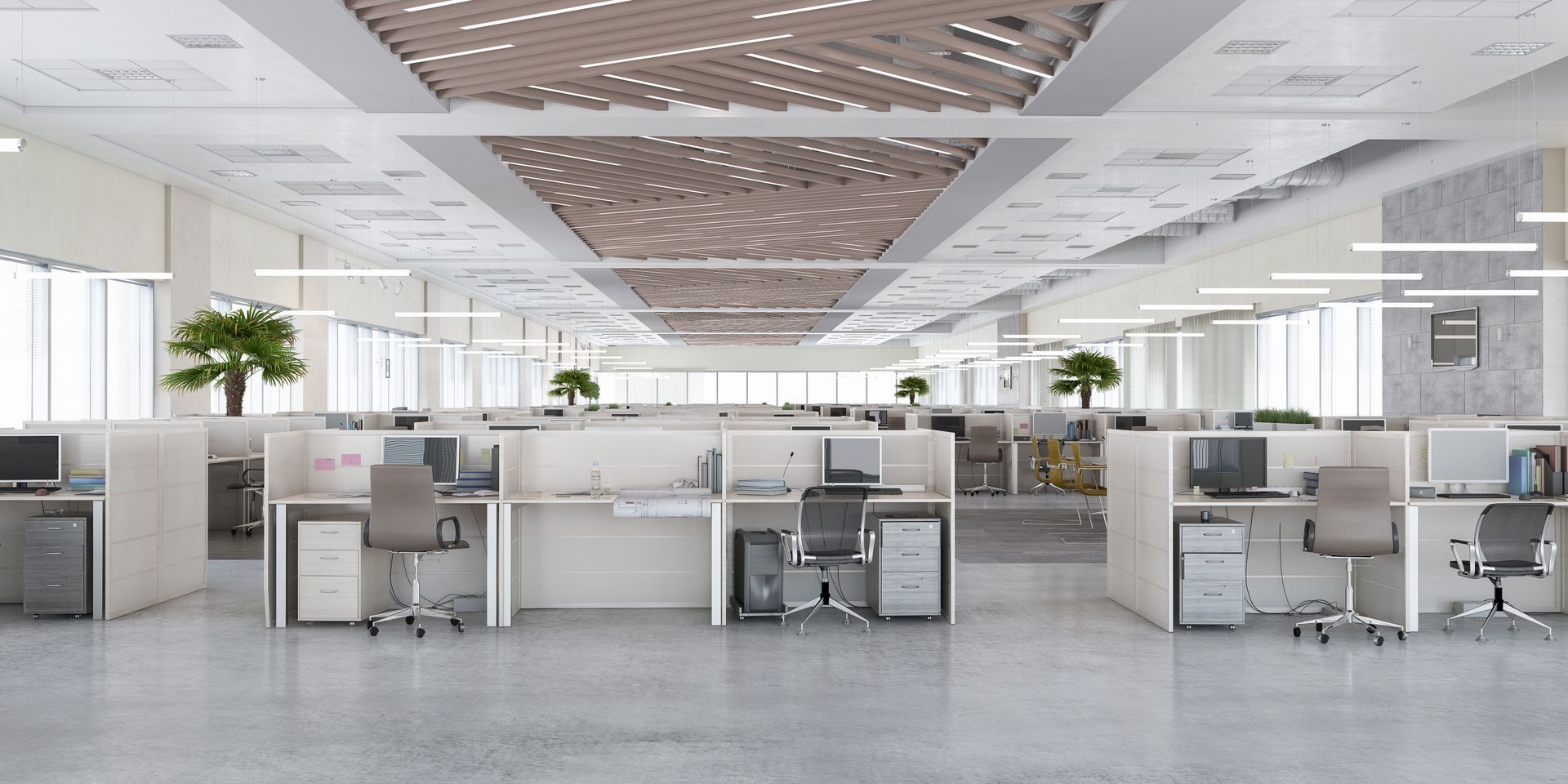 Modern open-plan office with desks, computers, and bright ceiling lights