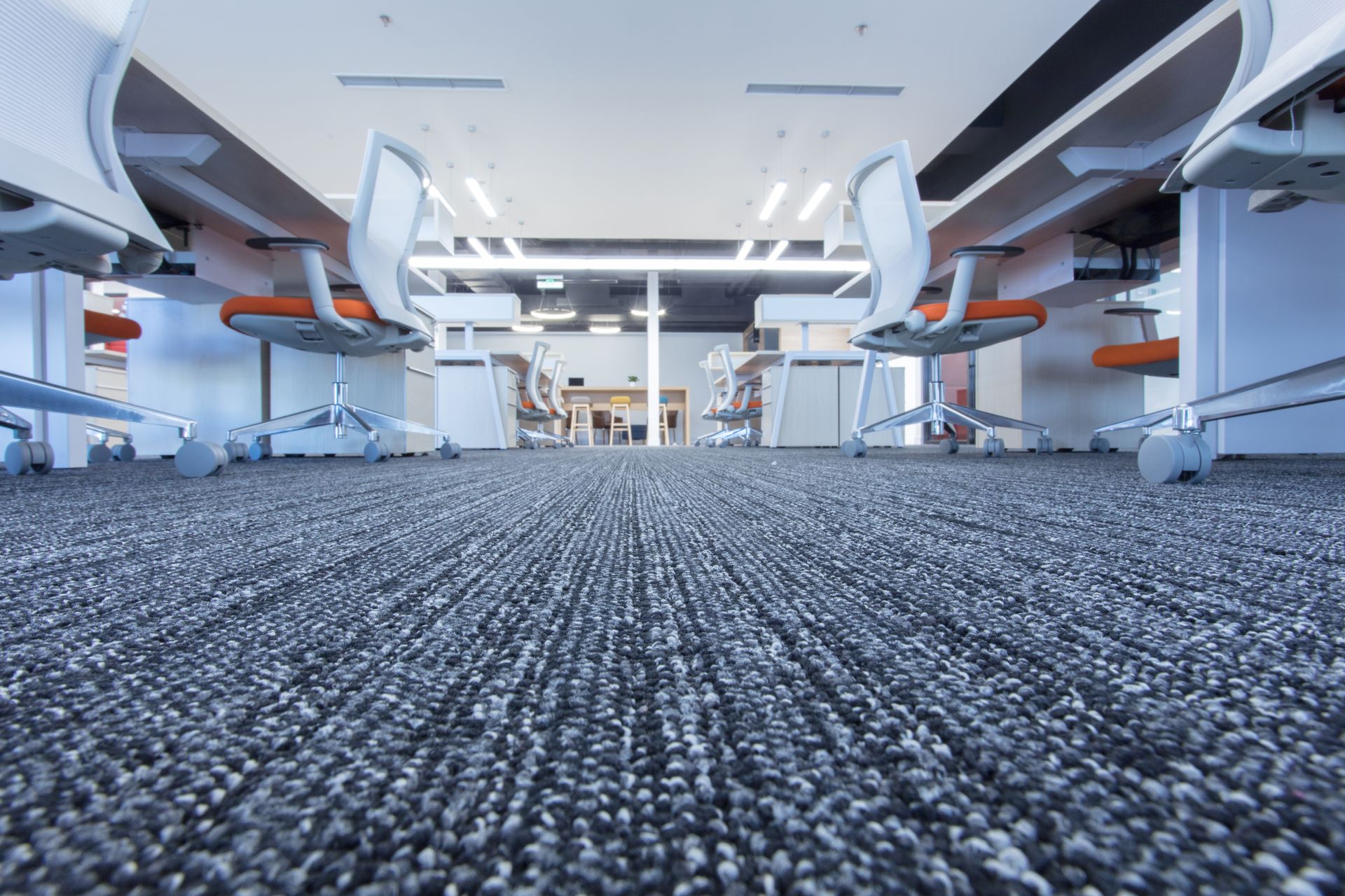 Modern office interior with rows of white desks and chairs on a gray carpet