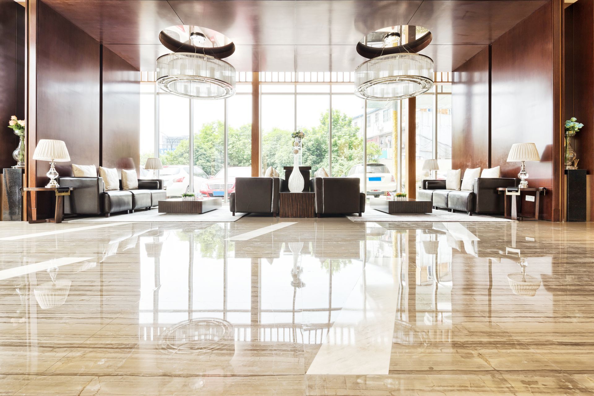 Luxurious hotel lobby with polished marble floors, seating, and large windows overlooking greenery
