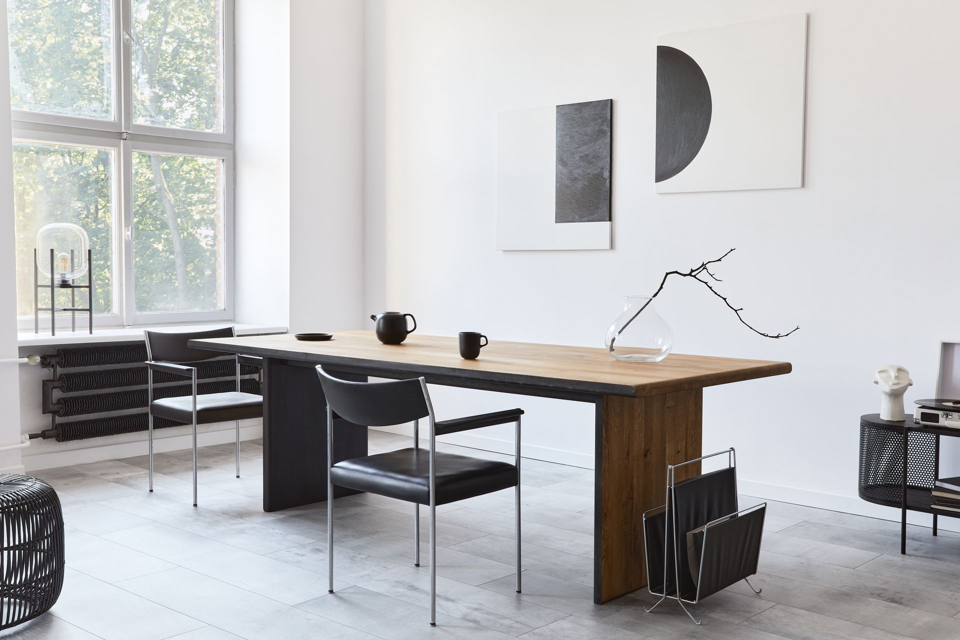 Minimal modern home office with wood desk, black chair, large window, and abstract wall art