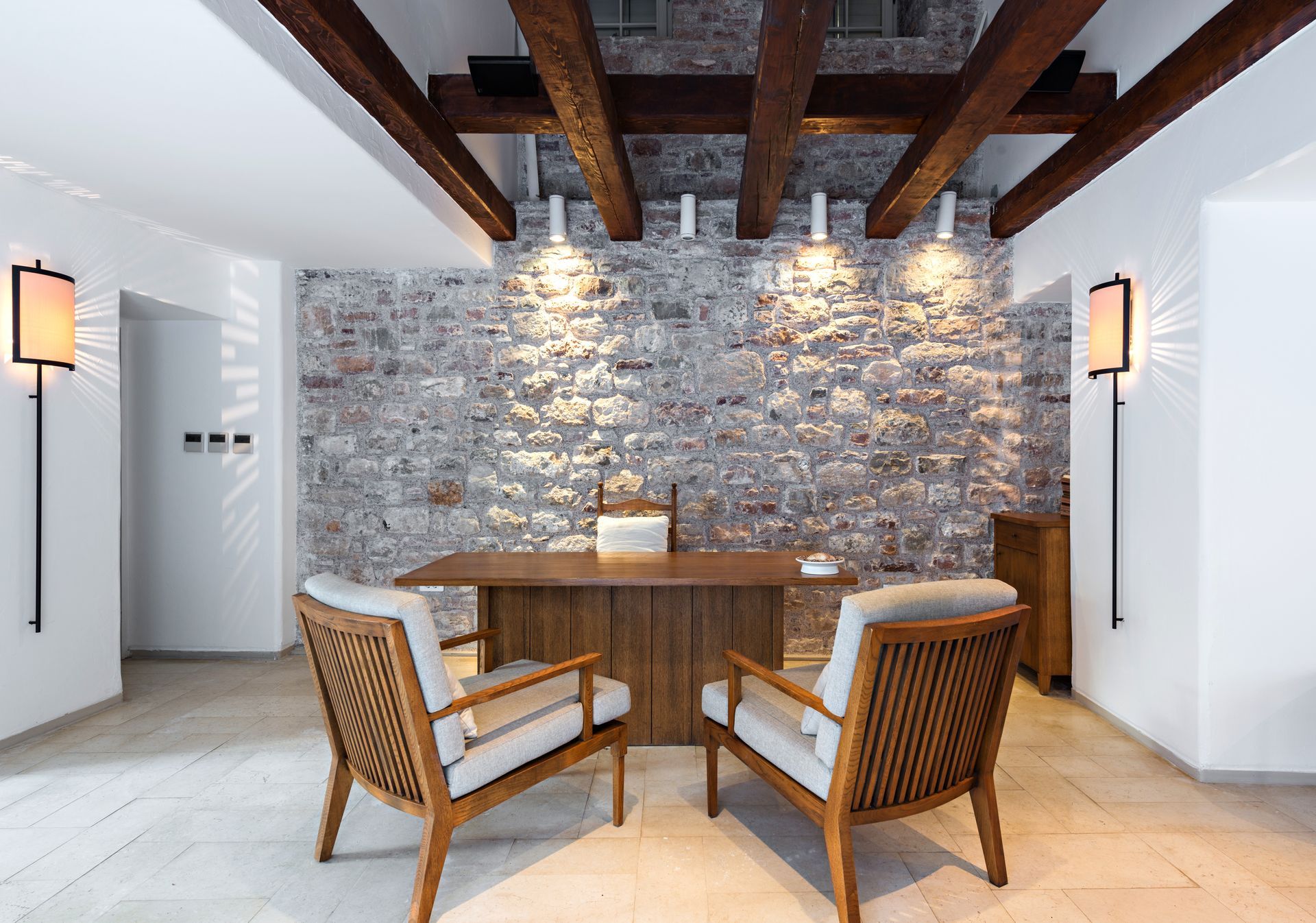 Modern dining nook with wooden table and chairs, stone accent wall, and exposed ceiling beams