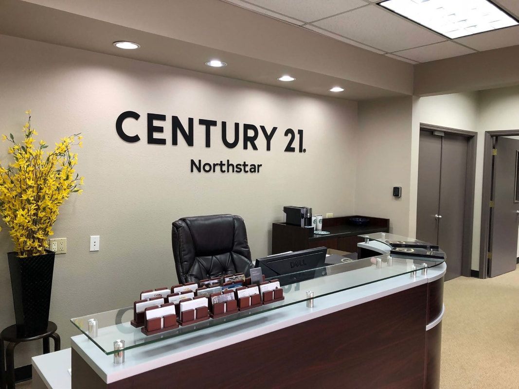 Century 21 Northstar real estate office reception desk with glass countertop and black leather chair