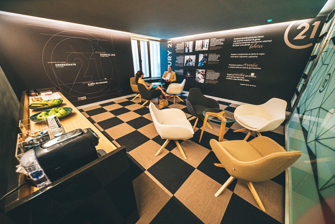 Modern lounge with black-and-white checkered floor, yellow chairs, and wall displays