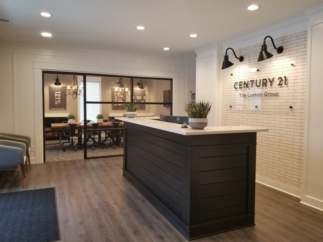 Modern hotel lobby with a dark wood front desk, white brick wall, and seating area behind glass doors