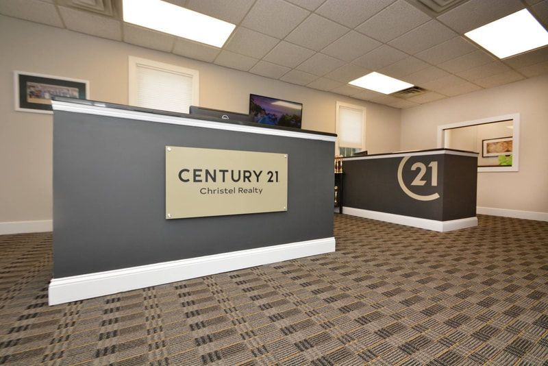 Century 21 real estate office lobby with gray walls, carpet, and reception desk