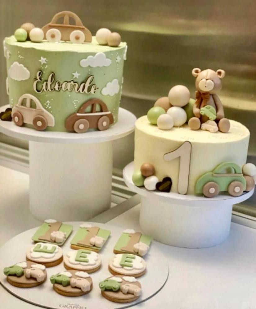 Due torte decorate e biscotti su piedistalli; una festa per il primo compleanno a tema auto.