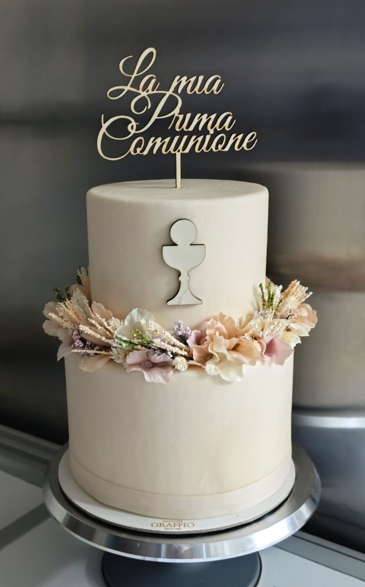 Torta a due piani con decorazione floreale e topper con la scritta