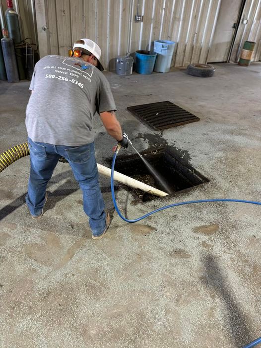 A man is cleaning a manhole cover with a hose.
