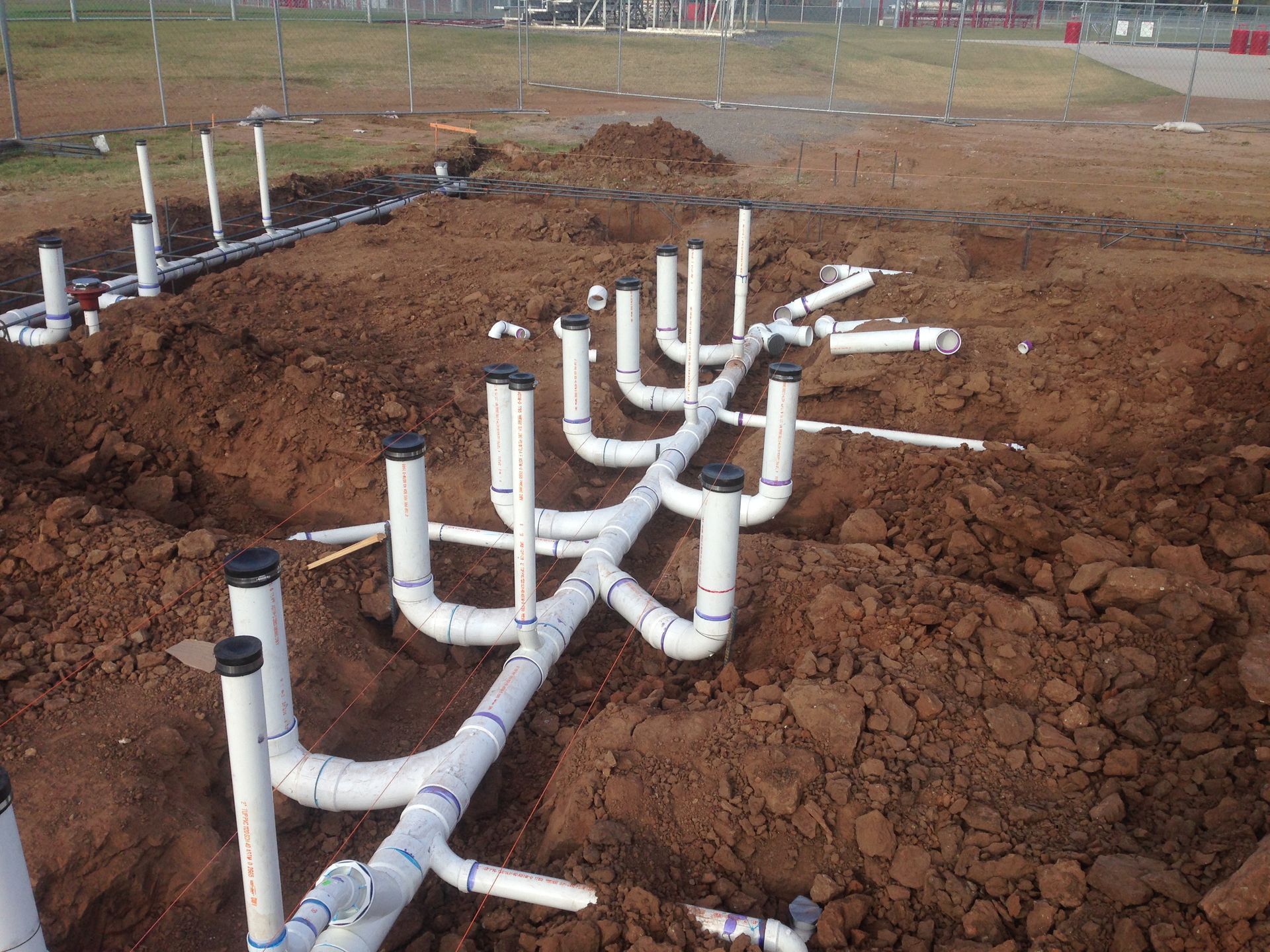 A bunch of white pipes are laying in the dirt