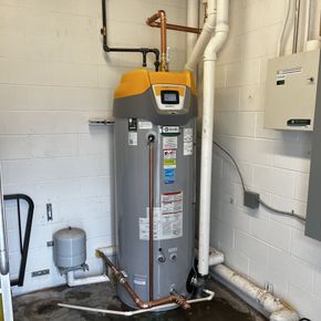 A water heater is sitting in a room next to a wall.