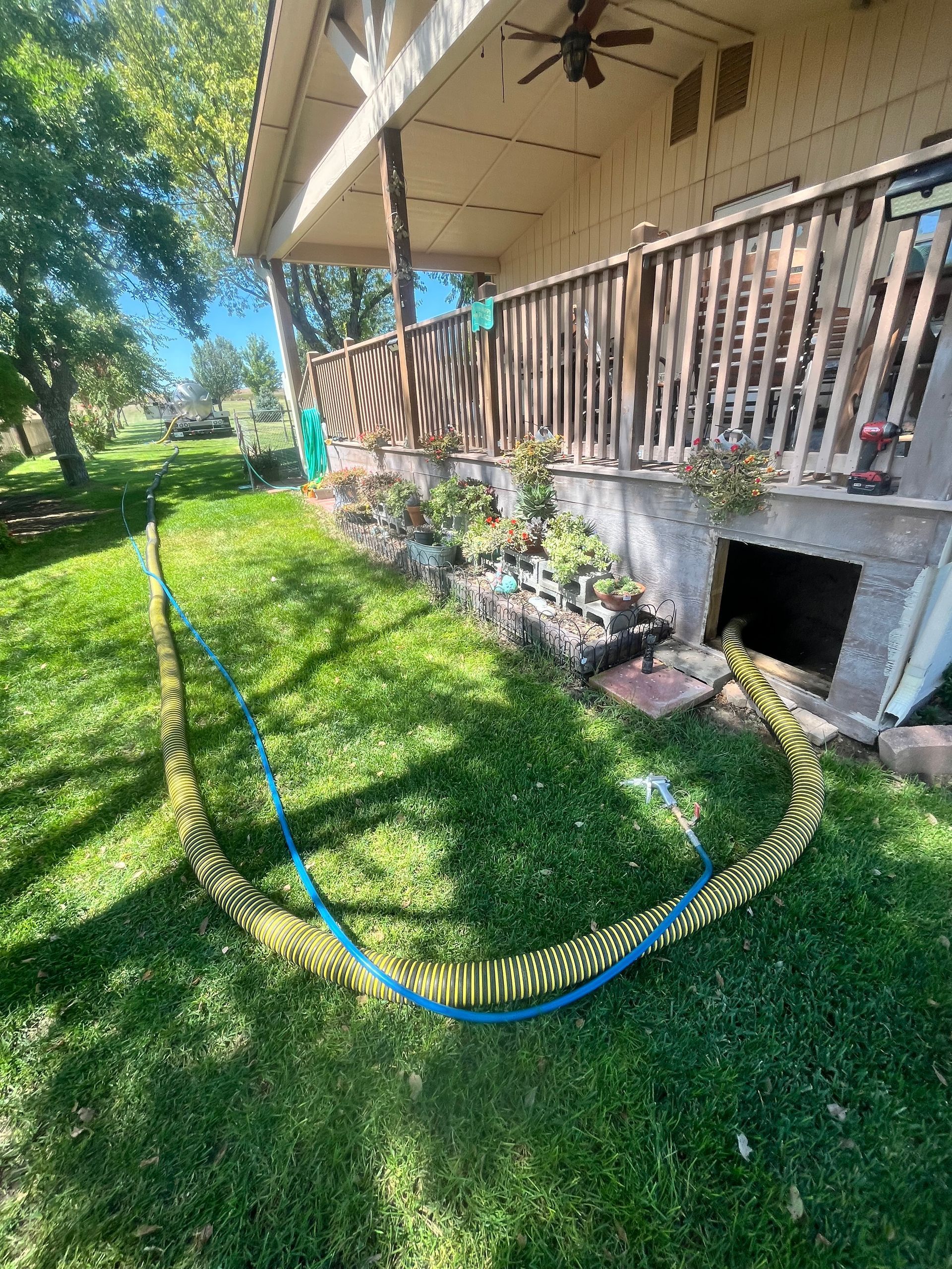 A hose is laying in the grass in front of a house.