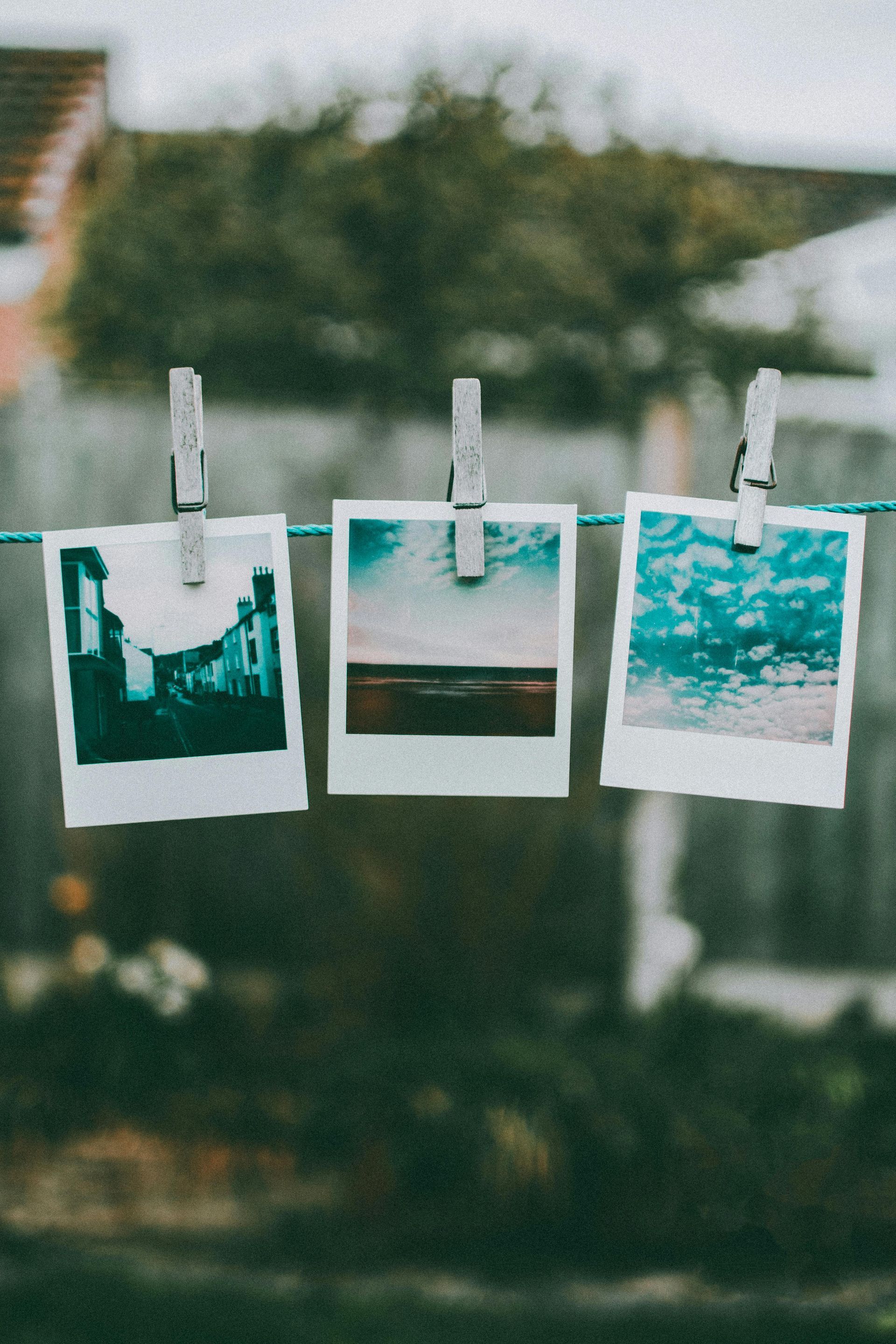 Three polaroid pictures are hanging on a clothes line.
