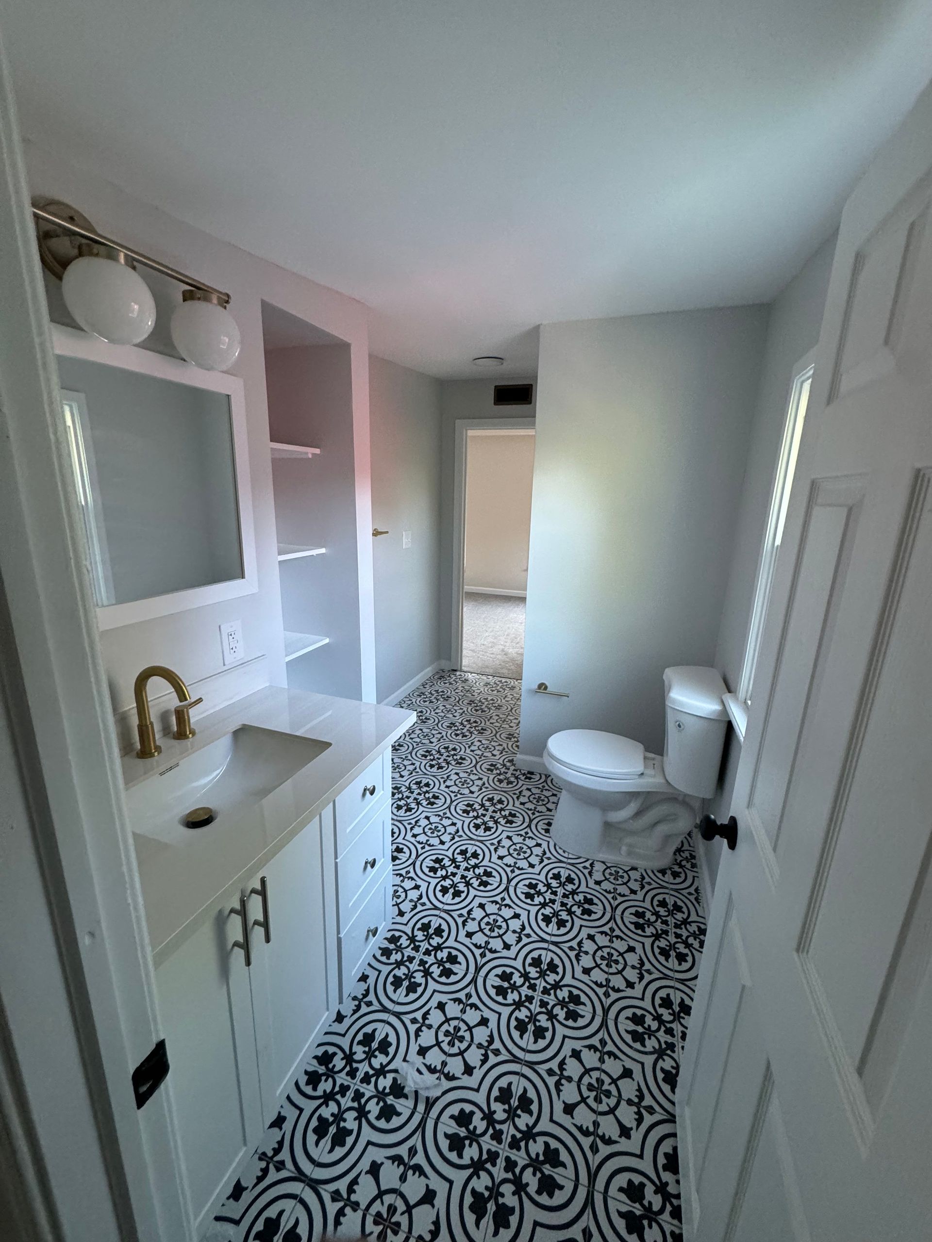 Bathroom with white vanity, patterned floor, and a toilet.