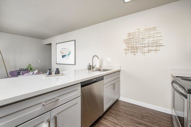 Bright modern kitchen with white cabinets, stainless sink, and wood flooring