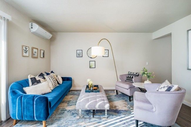 Bright living room with blue sofa, lavender chair, round coffee table, and wall art