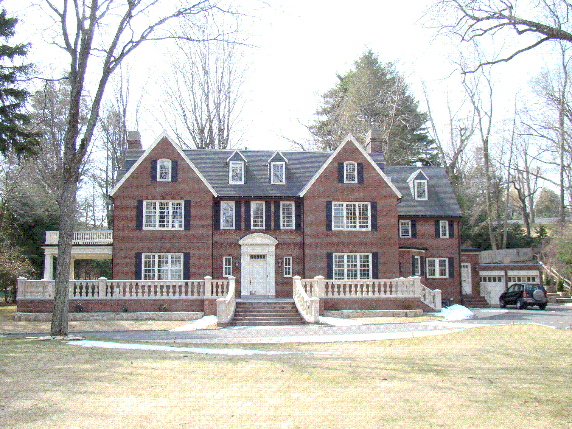 A large brick house with a black car parked in front of it