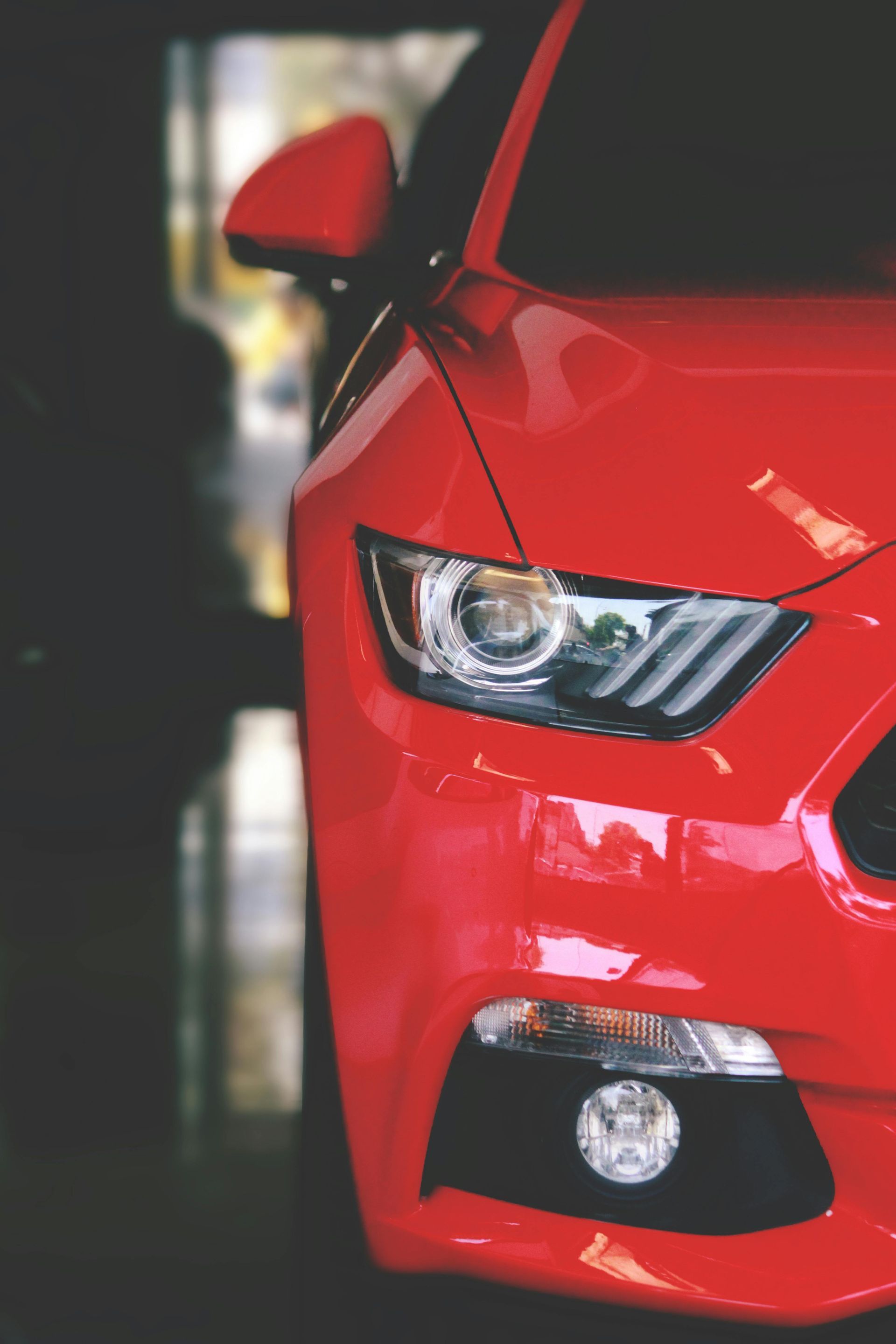 Red Ford Mustang, front view, headlight detail, parked indoors.