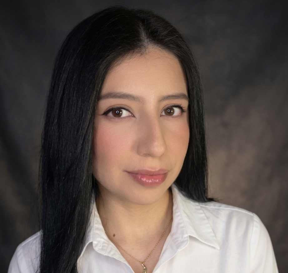 Portrait of a person with long dark hair in a white shirt against a dark gray studio background