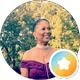 Smiling person in a maroon off-shoulder top, outdoors with blurred trees in the background.