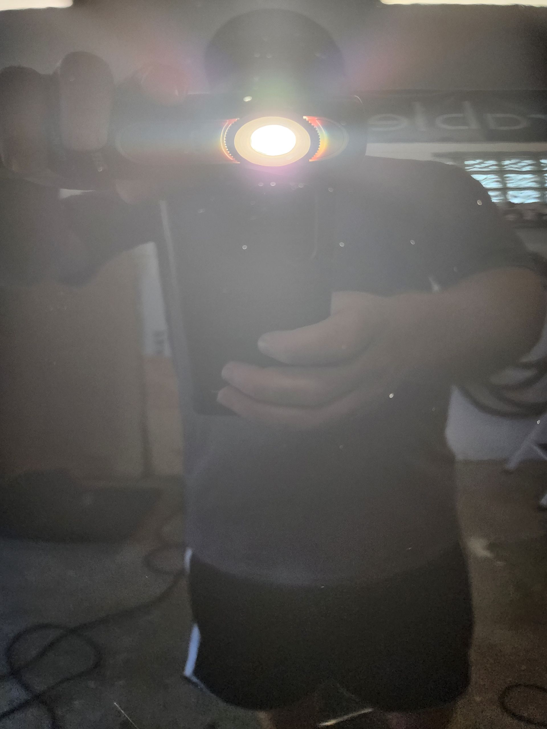 A person is taking a selfie with a flashlight on their head.