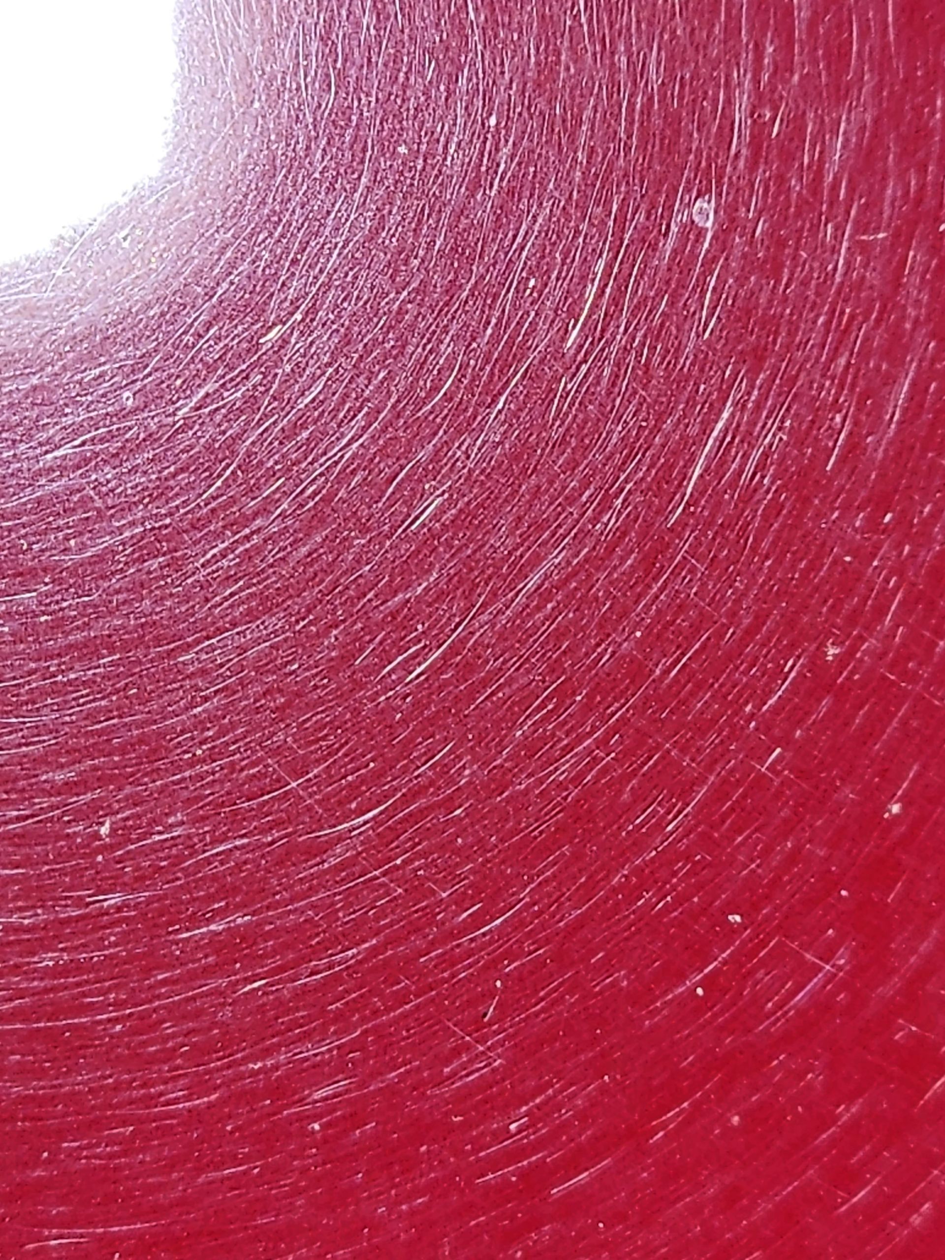 A close up of a red candle with a white background.