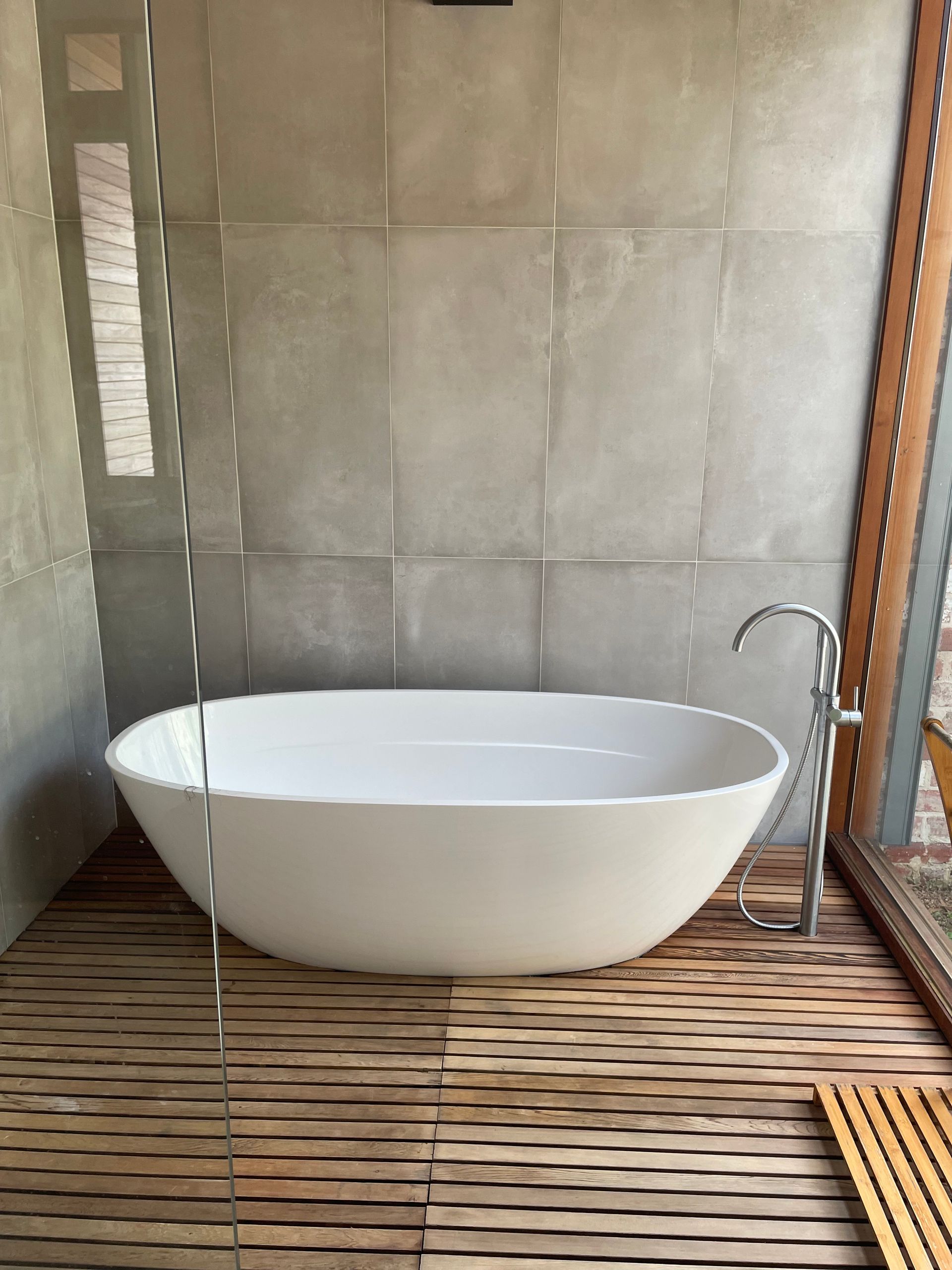 Modern White Bathroom with Gray Tile Floor, Soaking Tub, Shower — On The Rise Builders in North Arm, QLD