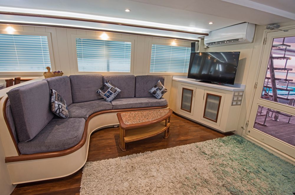 A Boat Interior with A Gray Sectional Sofa, TV — On The Rise Builders in North Arm, QLD