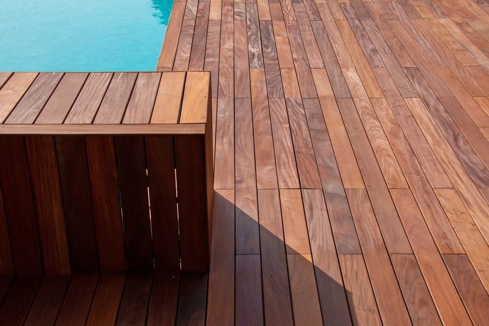 Wooden Pool Deck and Seating Area Next to Turquoise Water — On The Rise Builders in Caloundra, QLD