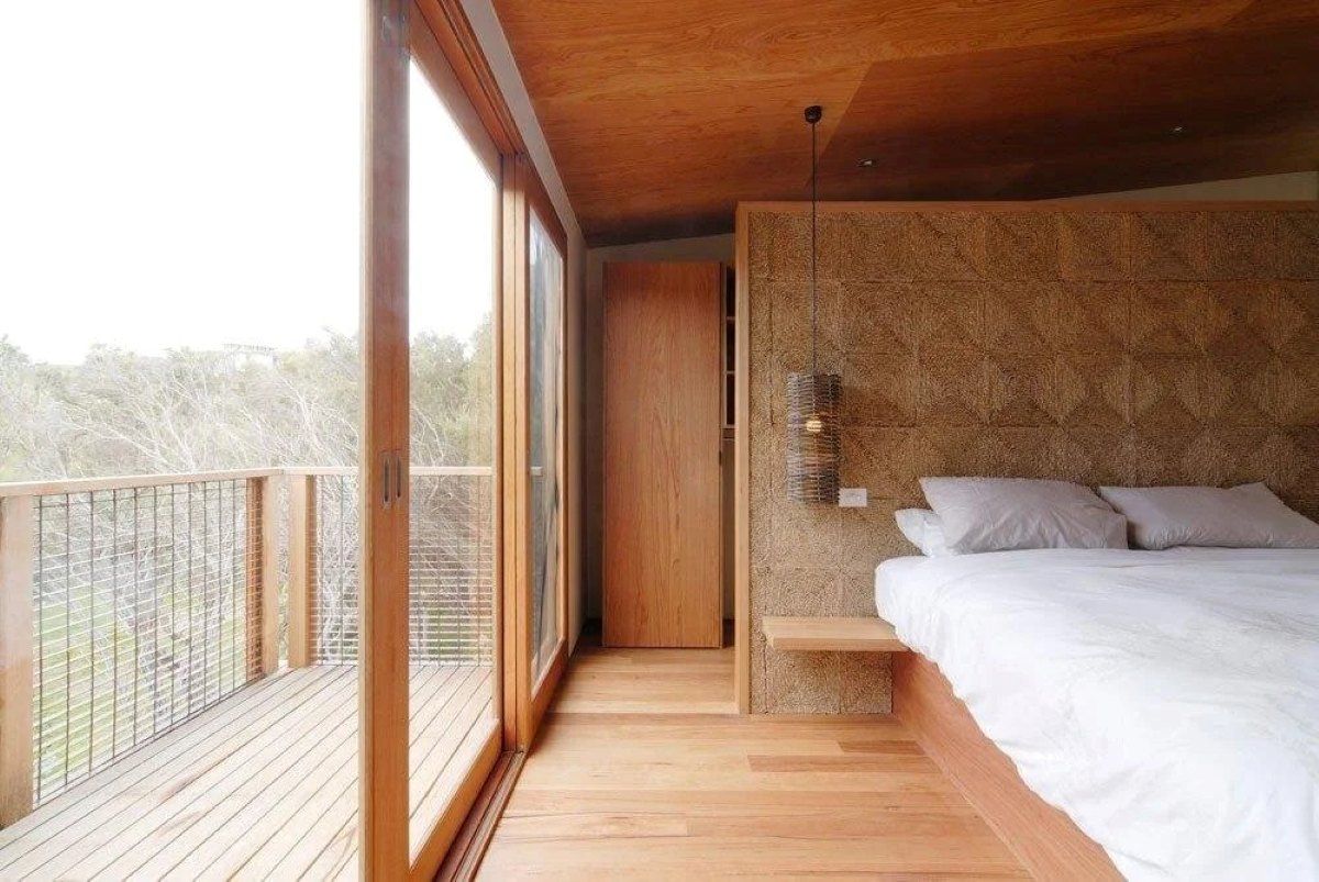 Bedroom with Wooden Walls, Bed, and Large Glass Doors — On The Rise Builders in North Arm, QLD