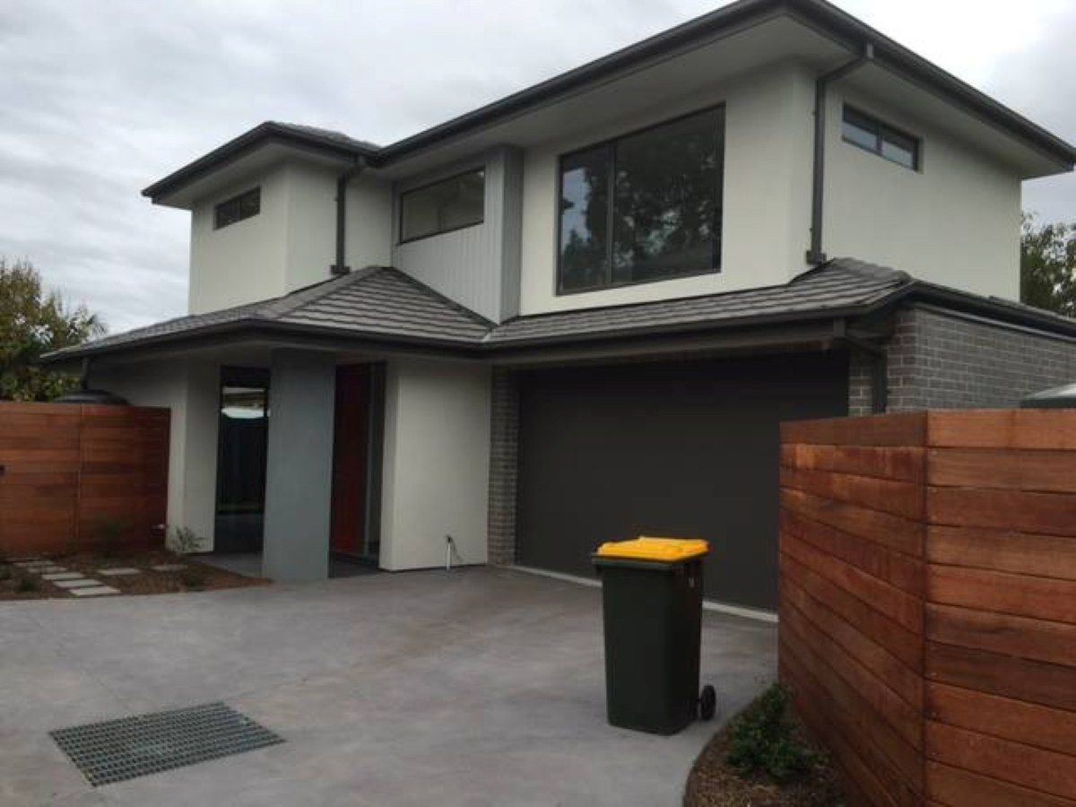 Two-Story Modern House with A Gray Garage Door and Wooden Fence — On The Rise Builders in Nambour, QLD