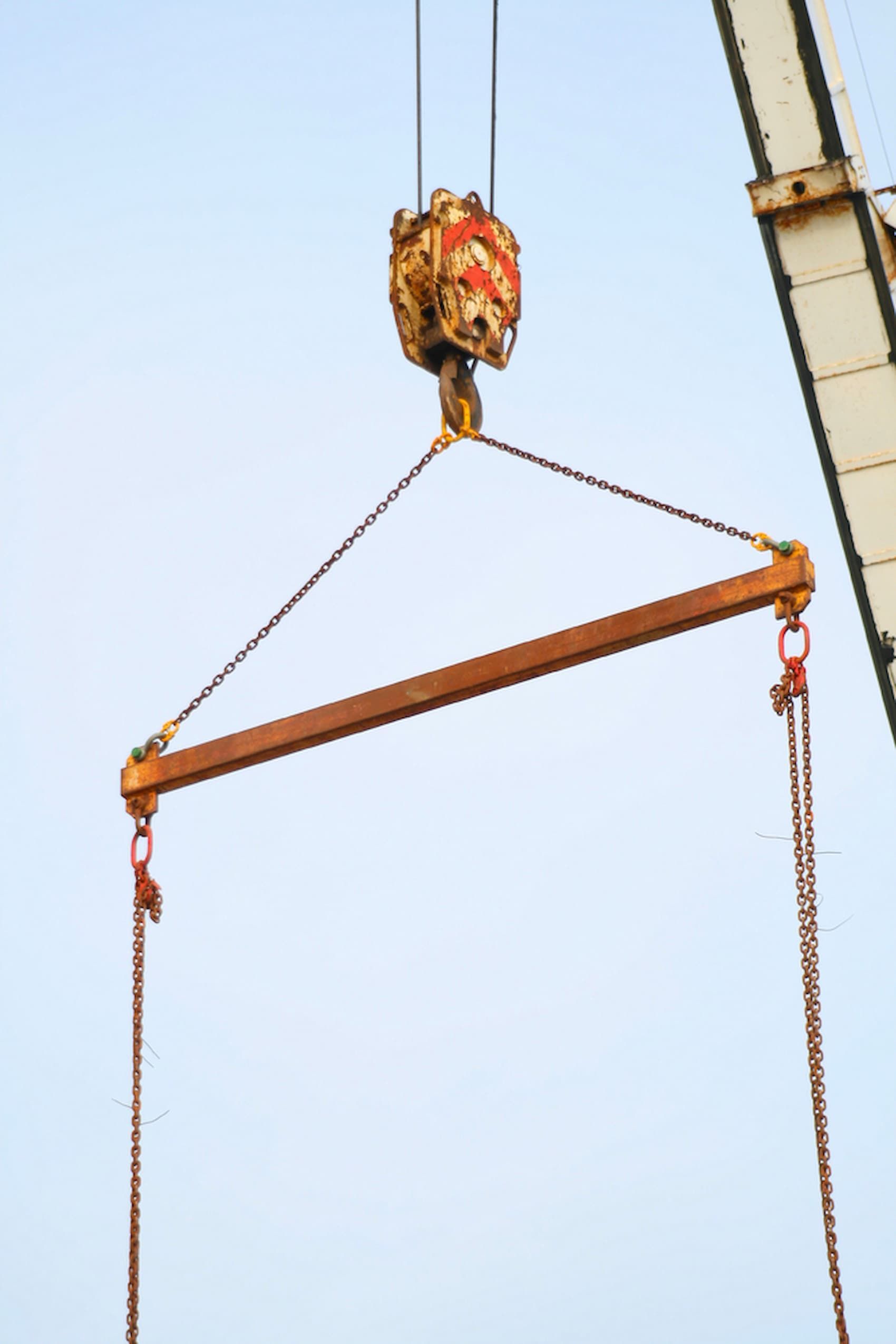A Crane Is Lifting a Wooden Bar with Chains Attached to It — D & S Crane Hire & Rigging In Maroochydore, QLD