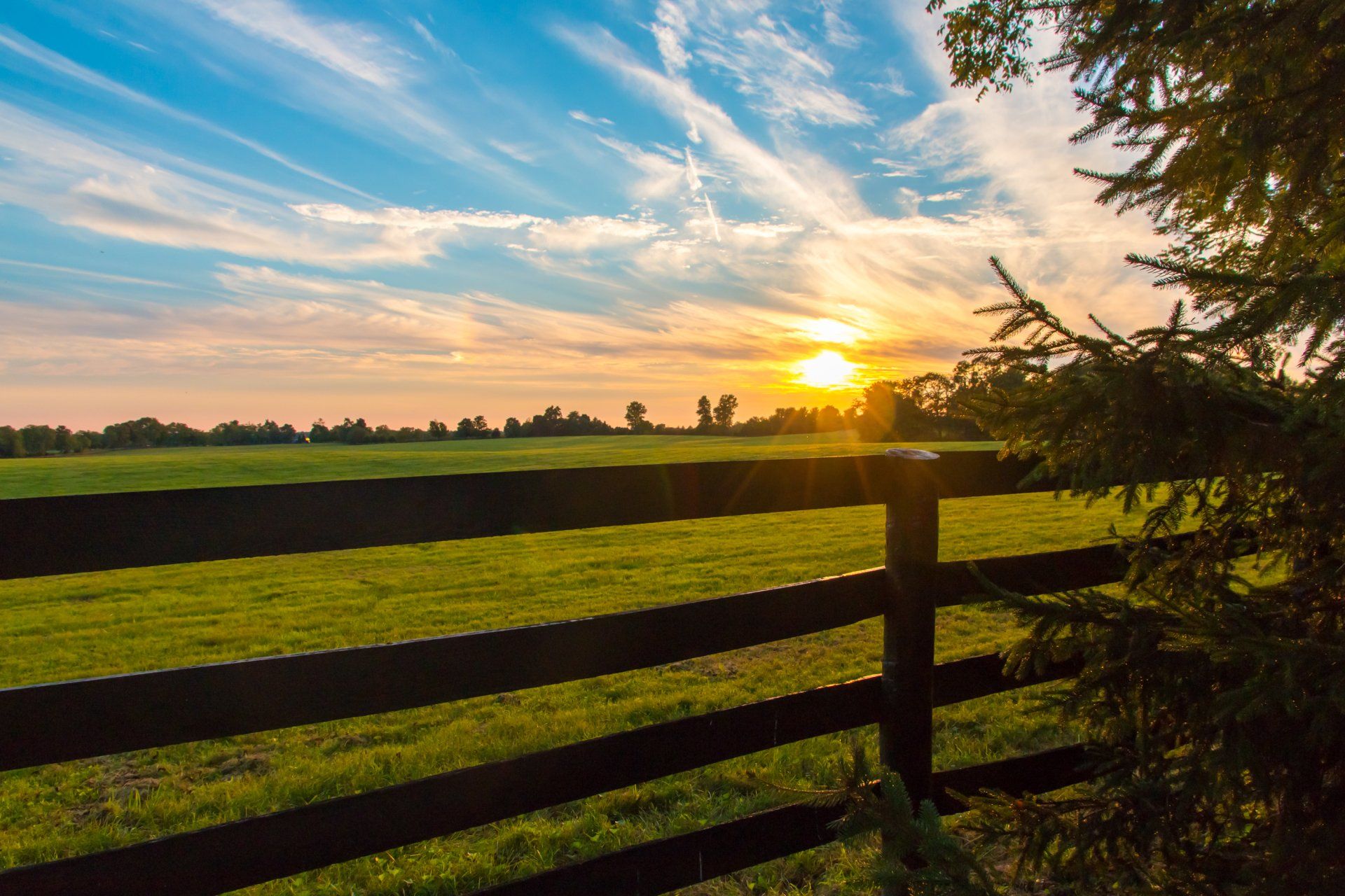The Sun Is Setting Behind a Wooden Fence in A Field —  D & S Crane Hire & Rigging In Kunda Park, QLD