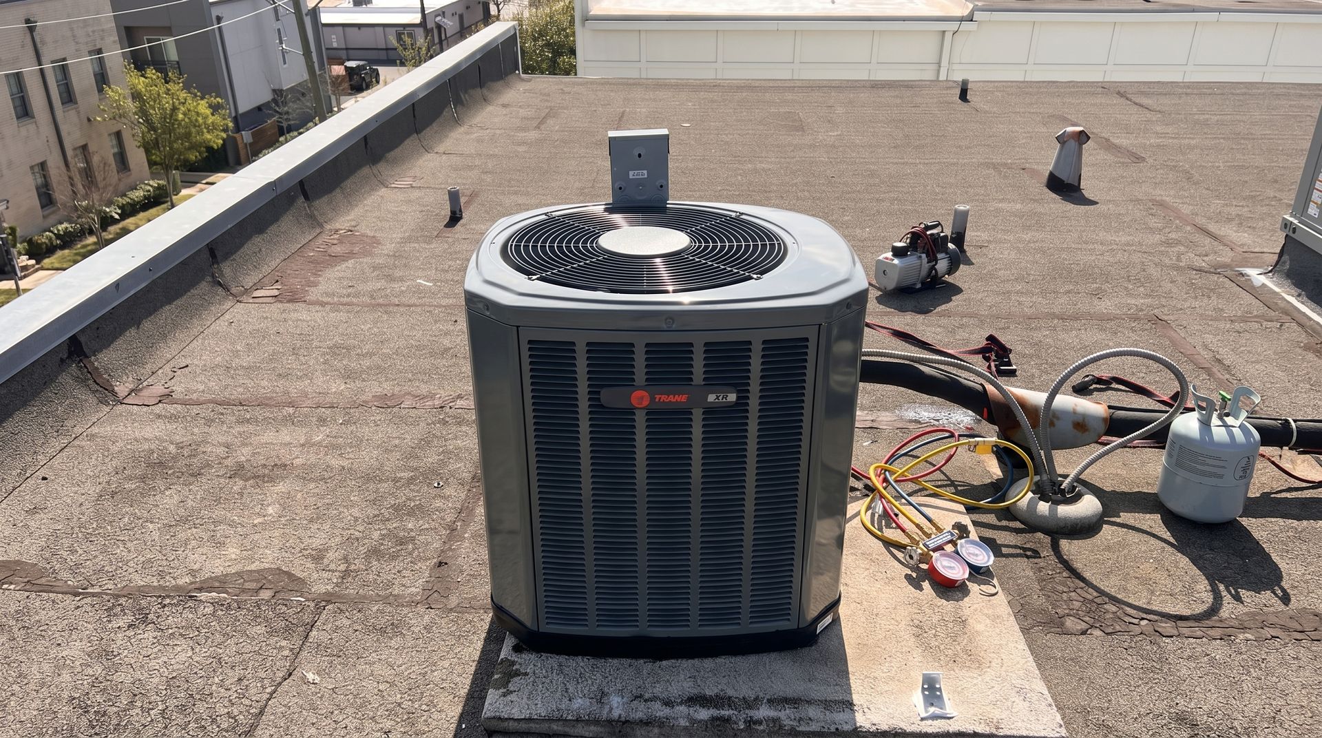 Technician servicing outdoor air conditioner units beside a brick building