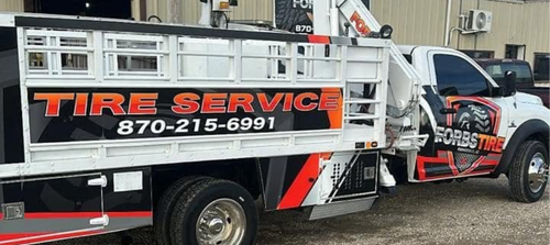Tire service truck with bold orange lettering and a service number parked outdoors.