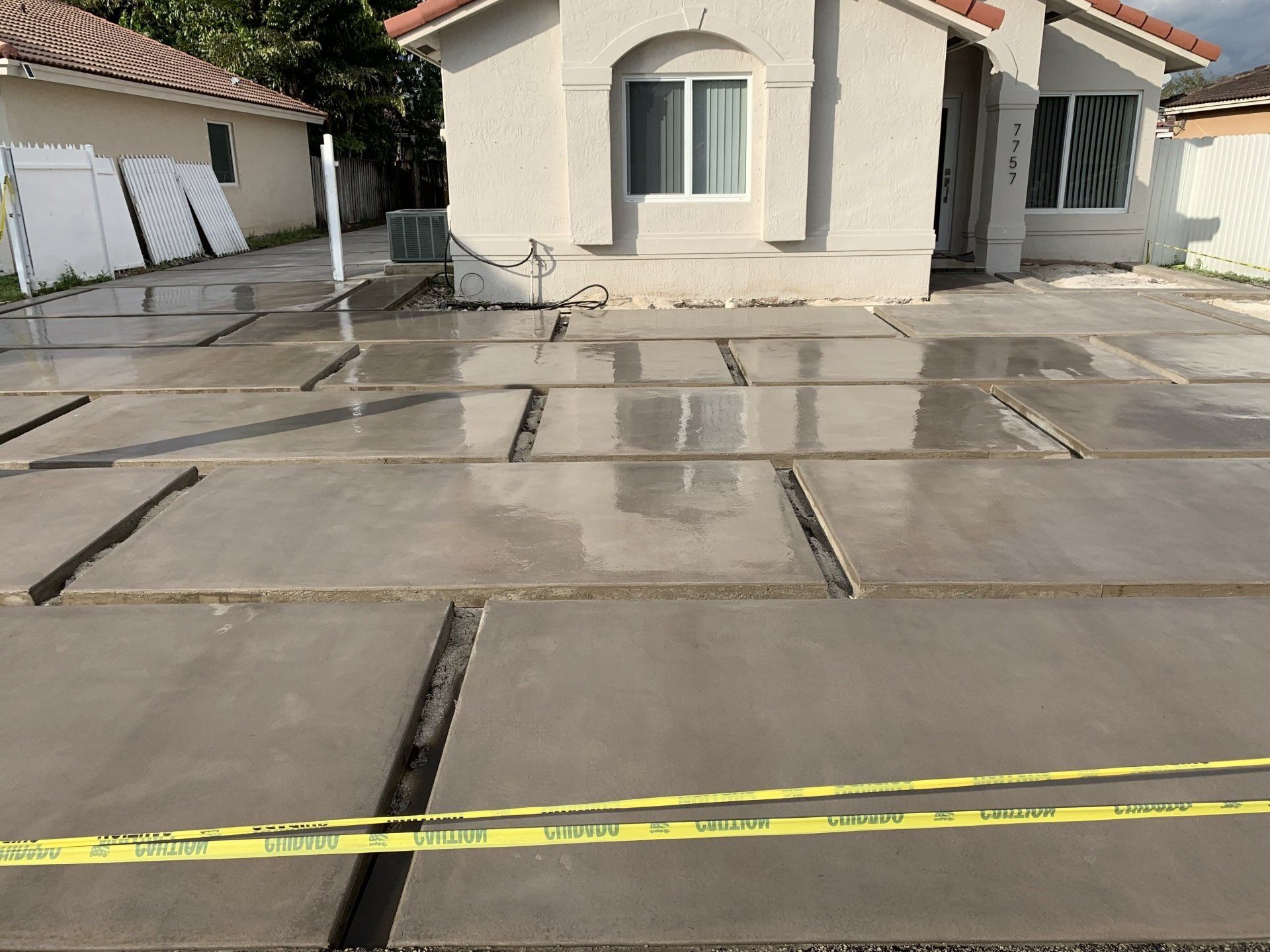 Newly poured concrete driveway with safety tape in front of a house.