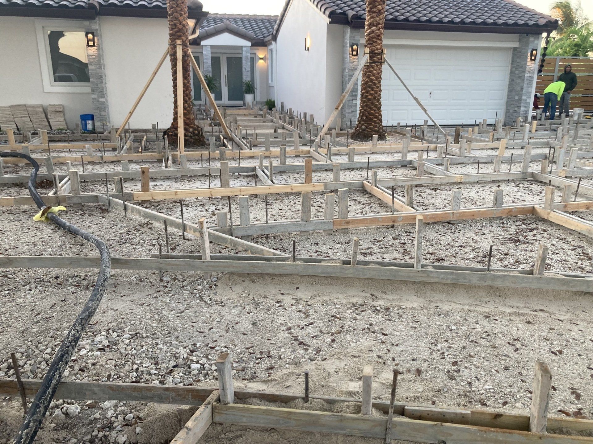 Construction site with concrete forms set up for a driveway in front of a house.