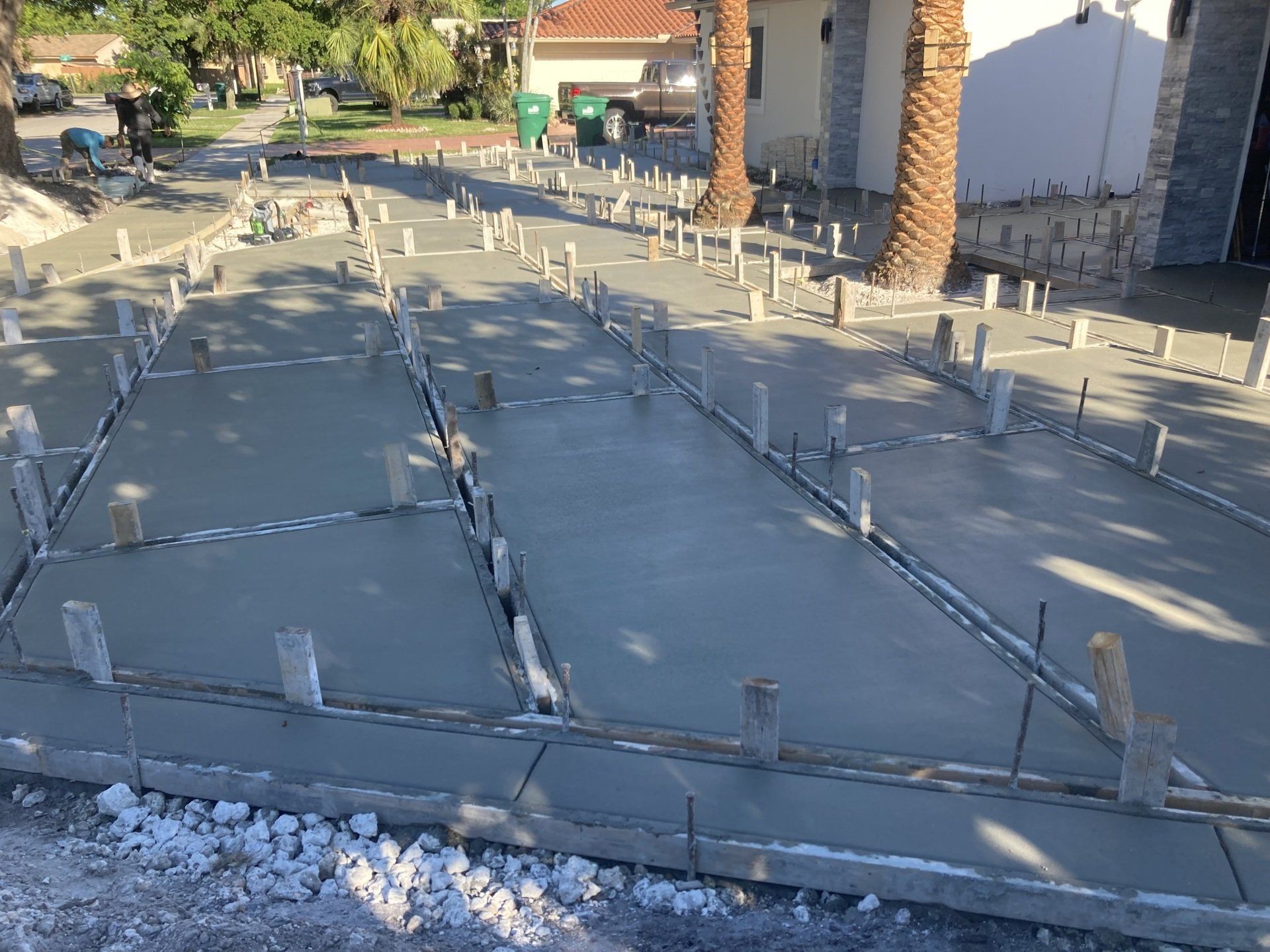 Freshly poured concrete driveway with wooden formwork and reinforcement bars.
