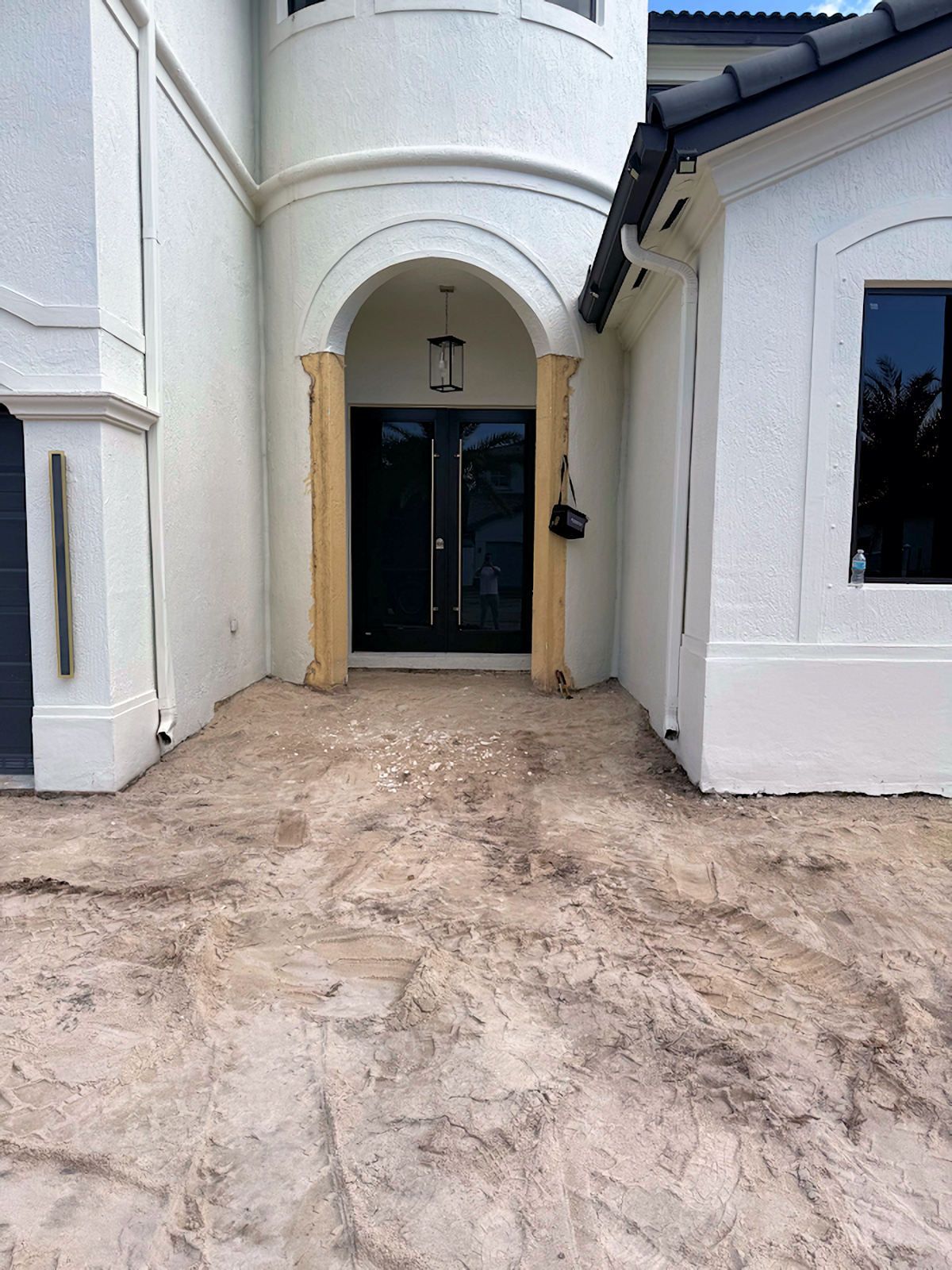 A large white house with a concrete driveway in front of it.