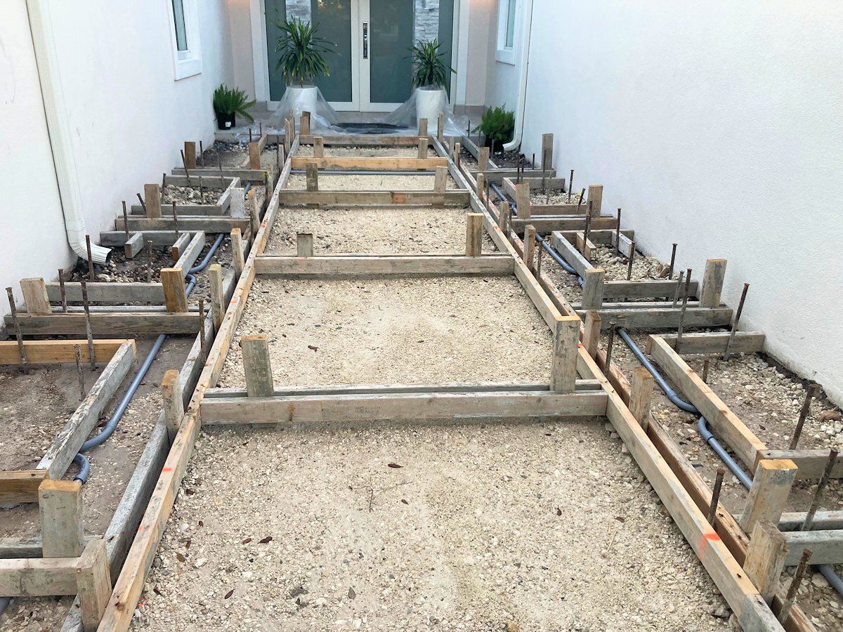 Concrete walkway under construction, wooden forms with gravel and rebar.
