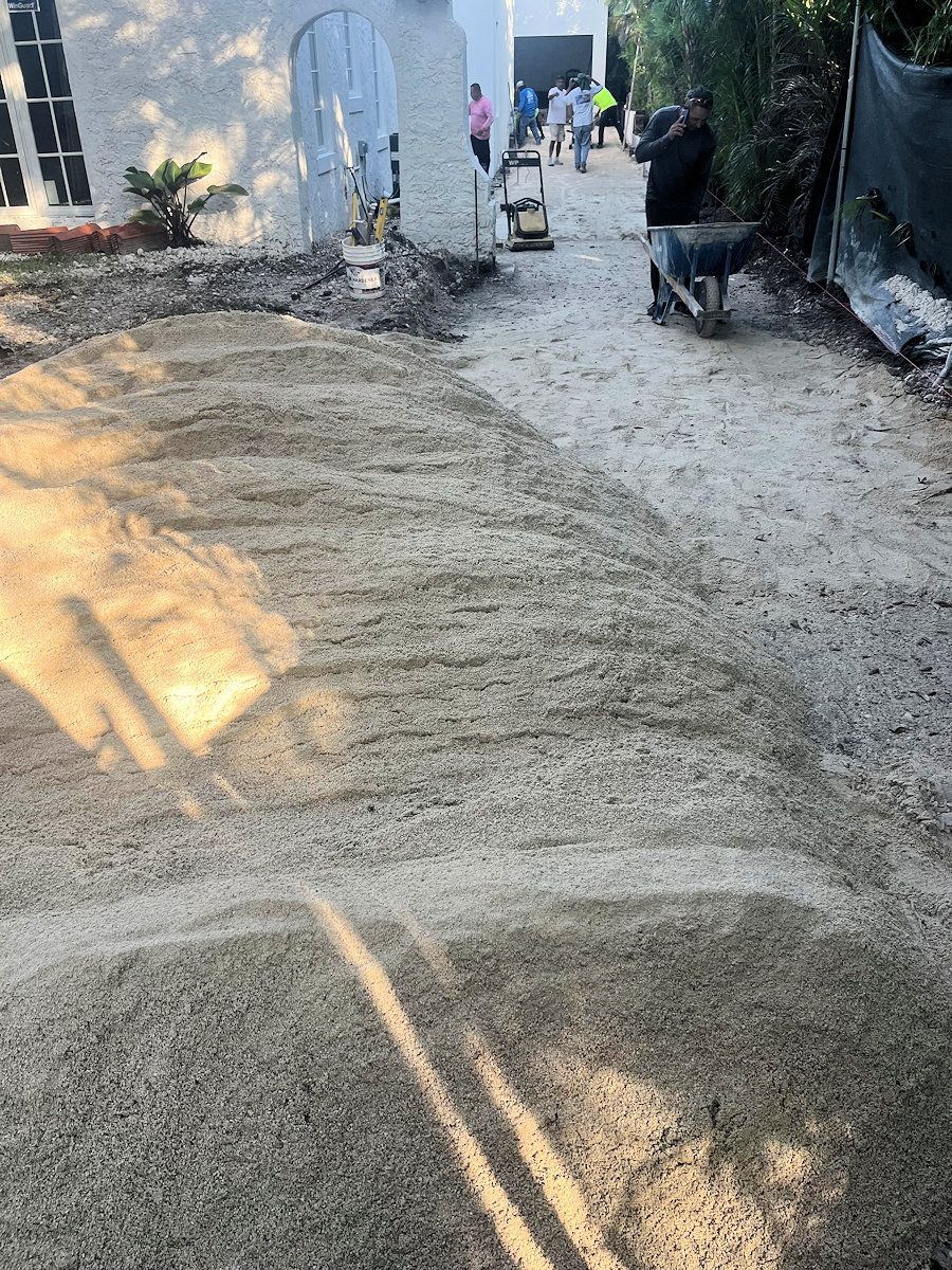 Gravel driveway under construction; workers and machinery visible.