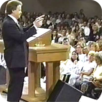 Speaker at podium addressing a seated audience in a lecture hall
