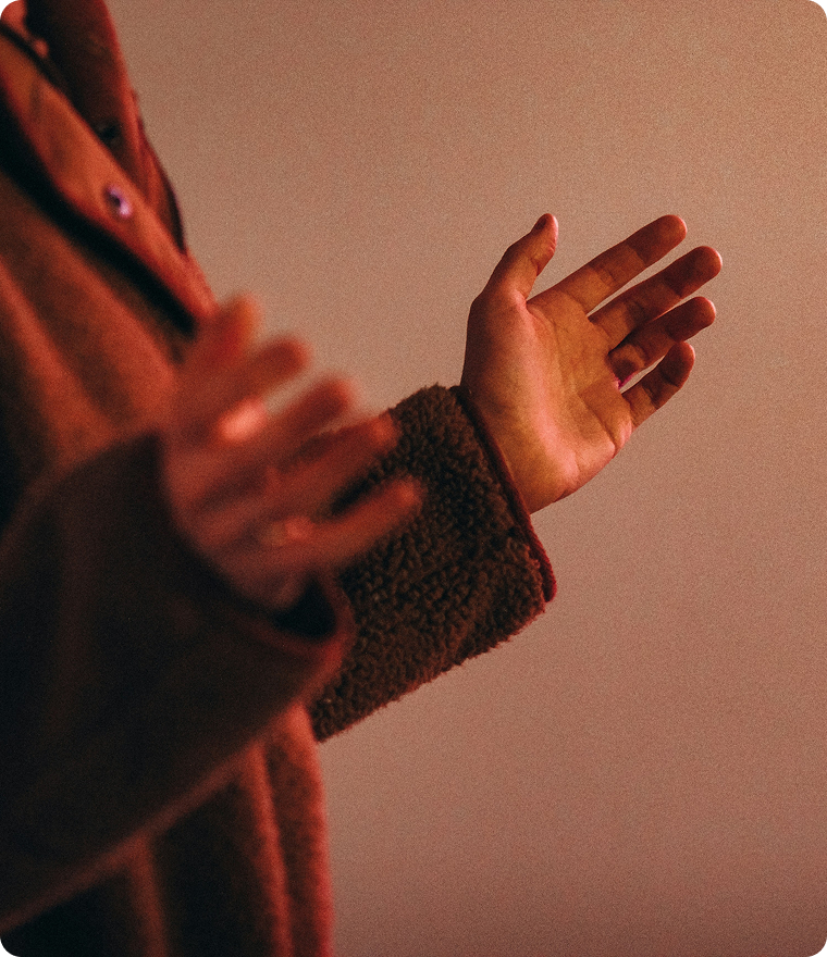 Hands raised in a warm-lit close-up against a plain background