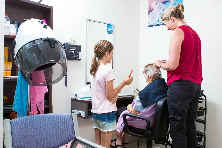 A woman is cutting a woman 's hair in a salon at Beauaraba Living.