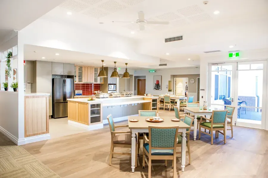 A large dining room with tables and chairs in the nursing home Beauaraba Living.