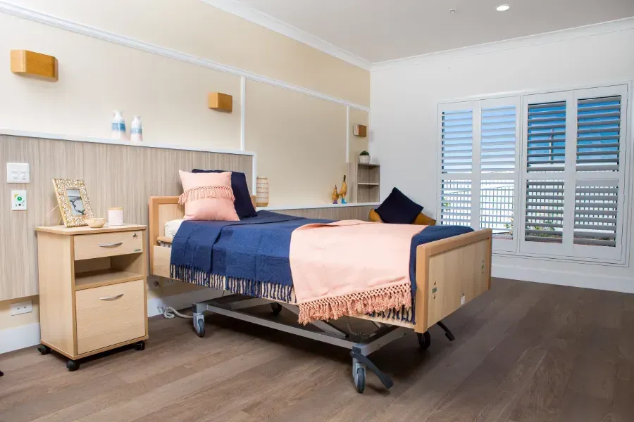 A single bed room at Beauaraba Living with a nightstand  and shutters.